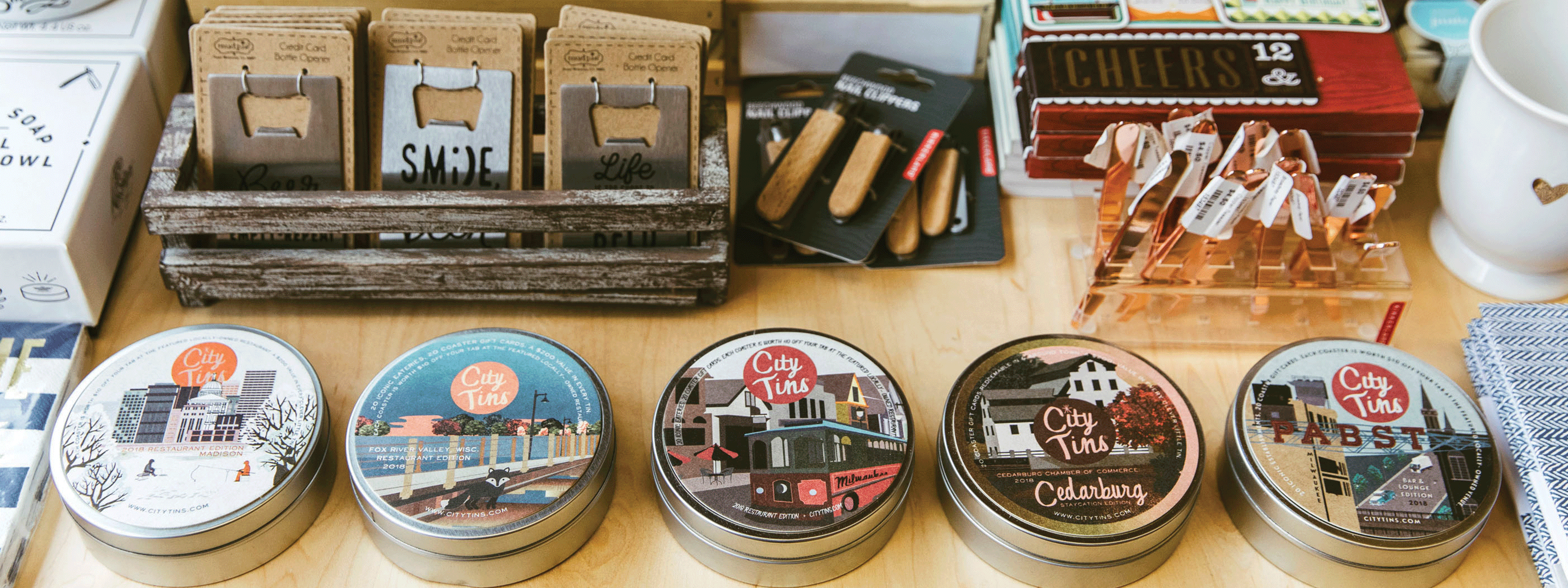 Retail display with five CityTins centrally positioned among other gift store items.