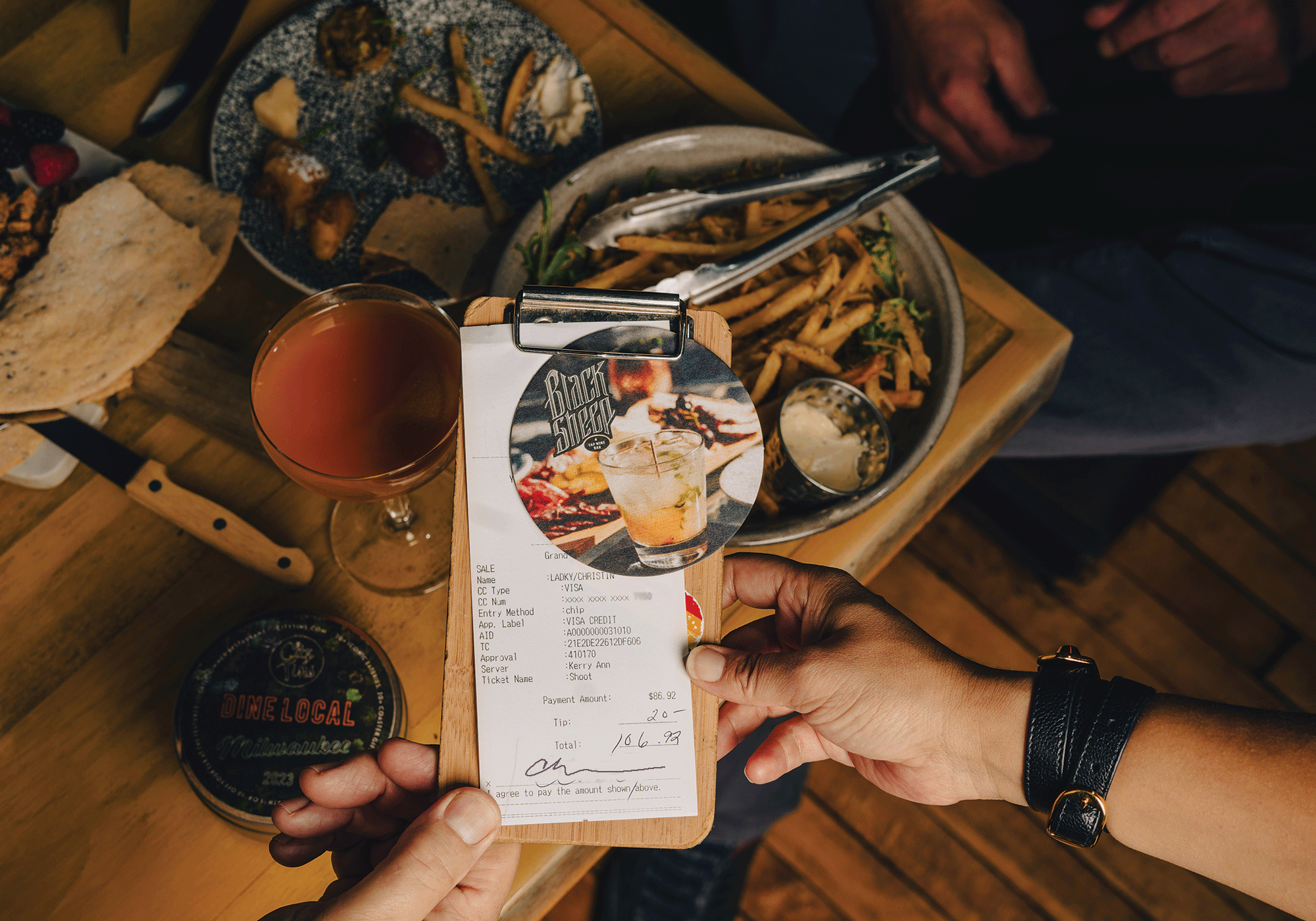 Dining table with a signed receipt, including restaurant coaster in checkholder presented to server.